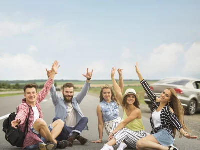 joyful-friends-sitting-road-raising-their-hands-gesturing